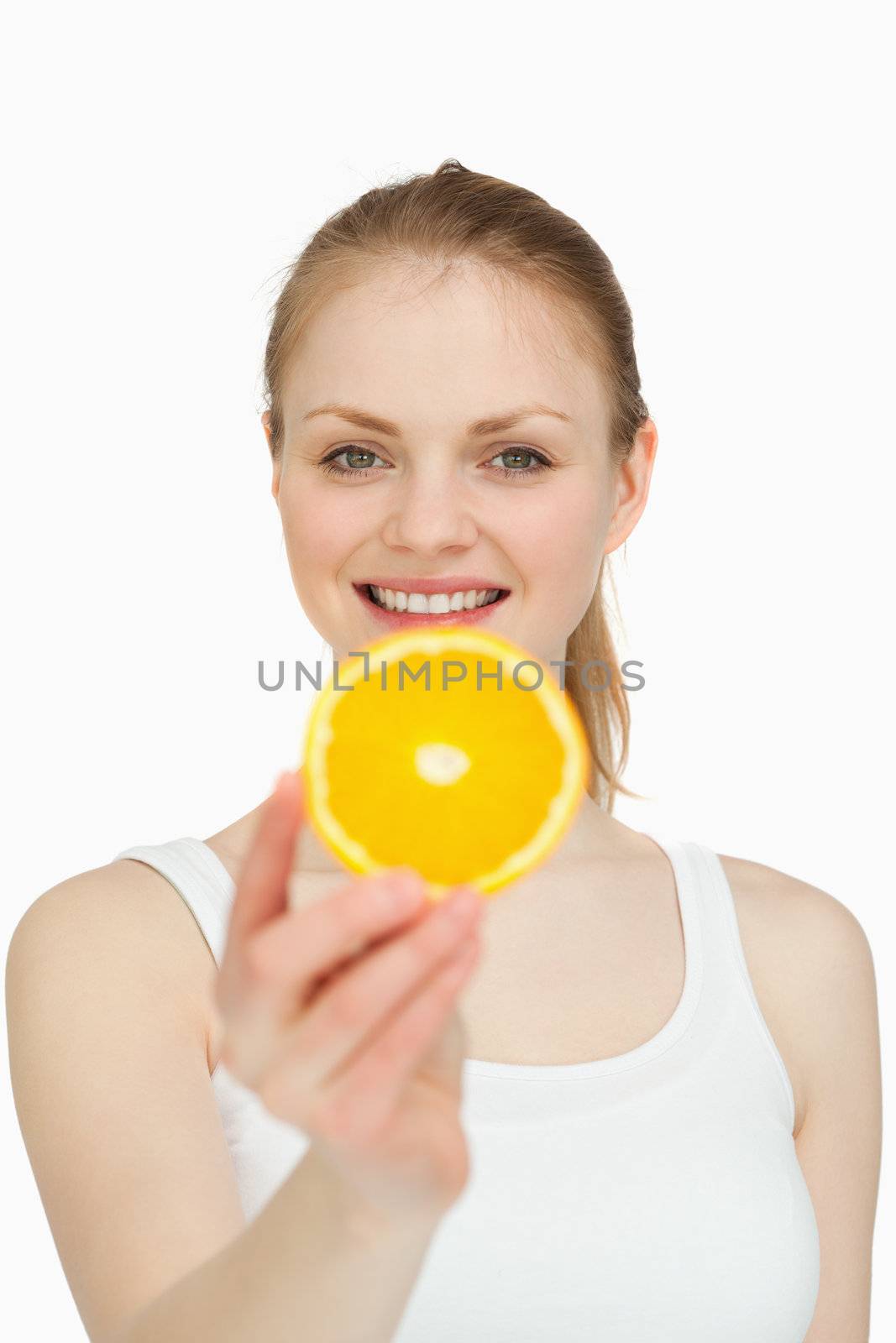 Smiling woman presenting a slice of orange against white background