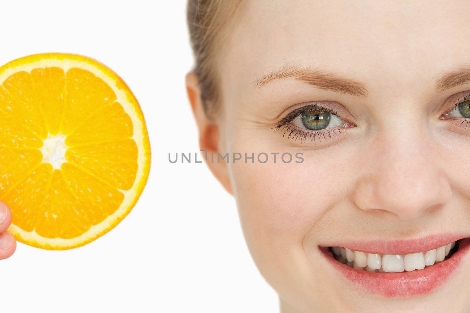 Close up of a woman presenting an orange slice against white background