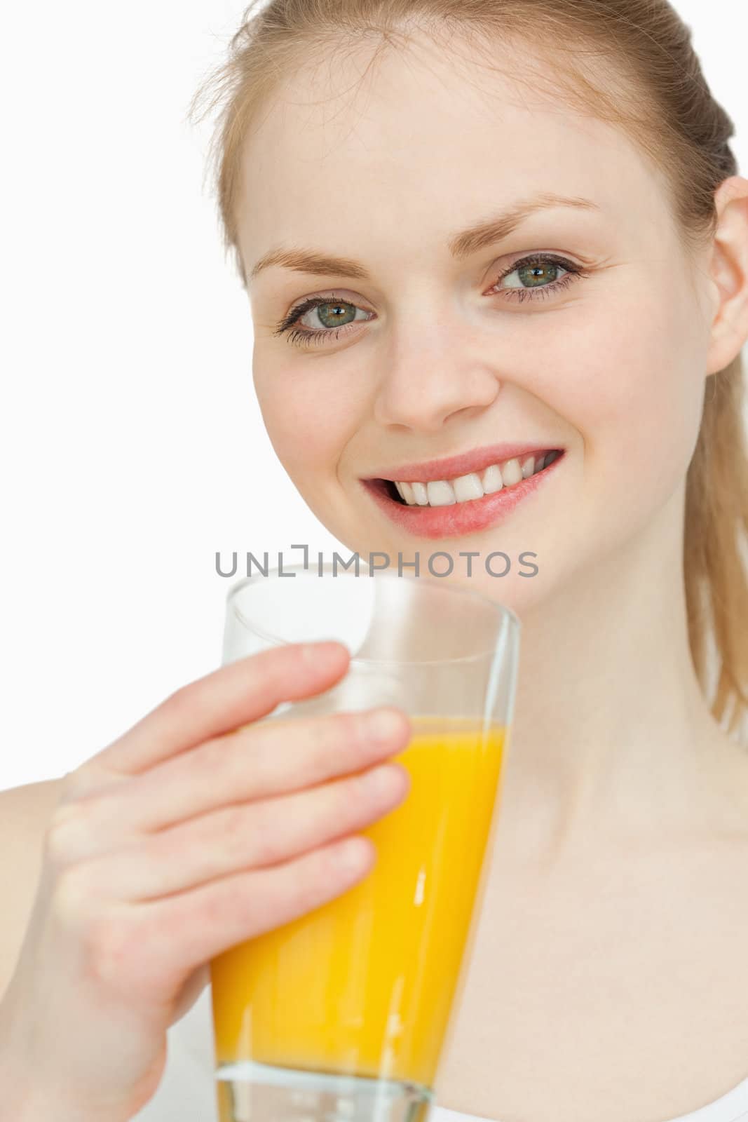 Cheerful woman holding a glass of orange juice against white background