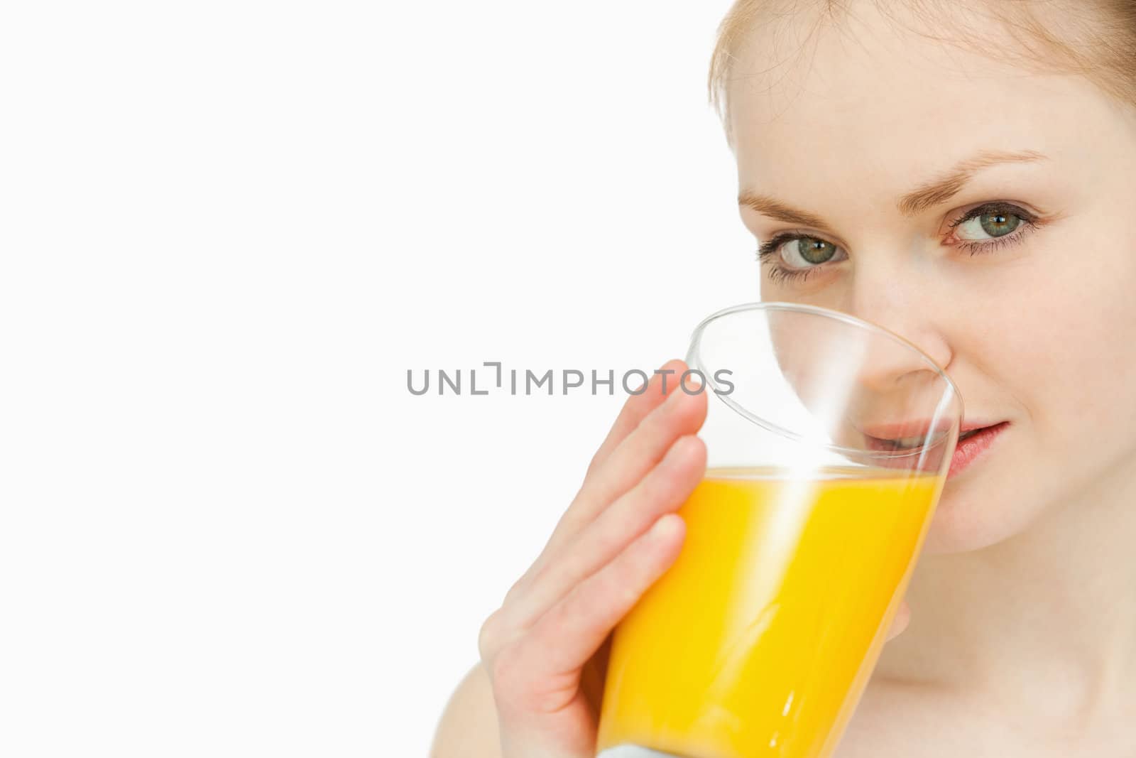 Young woman drinking a glass of orange juice against white background