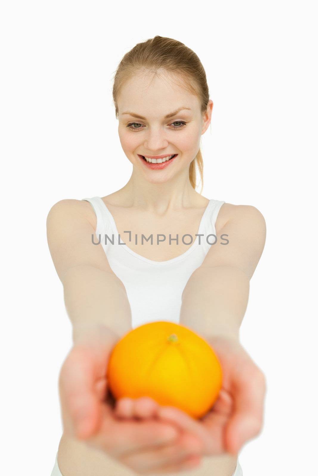 Woman presenting a tangerine while looking at it against white background