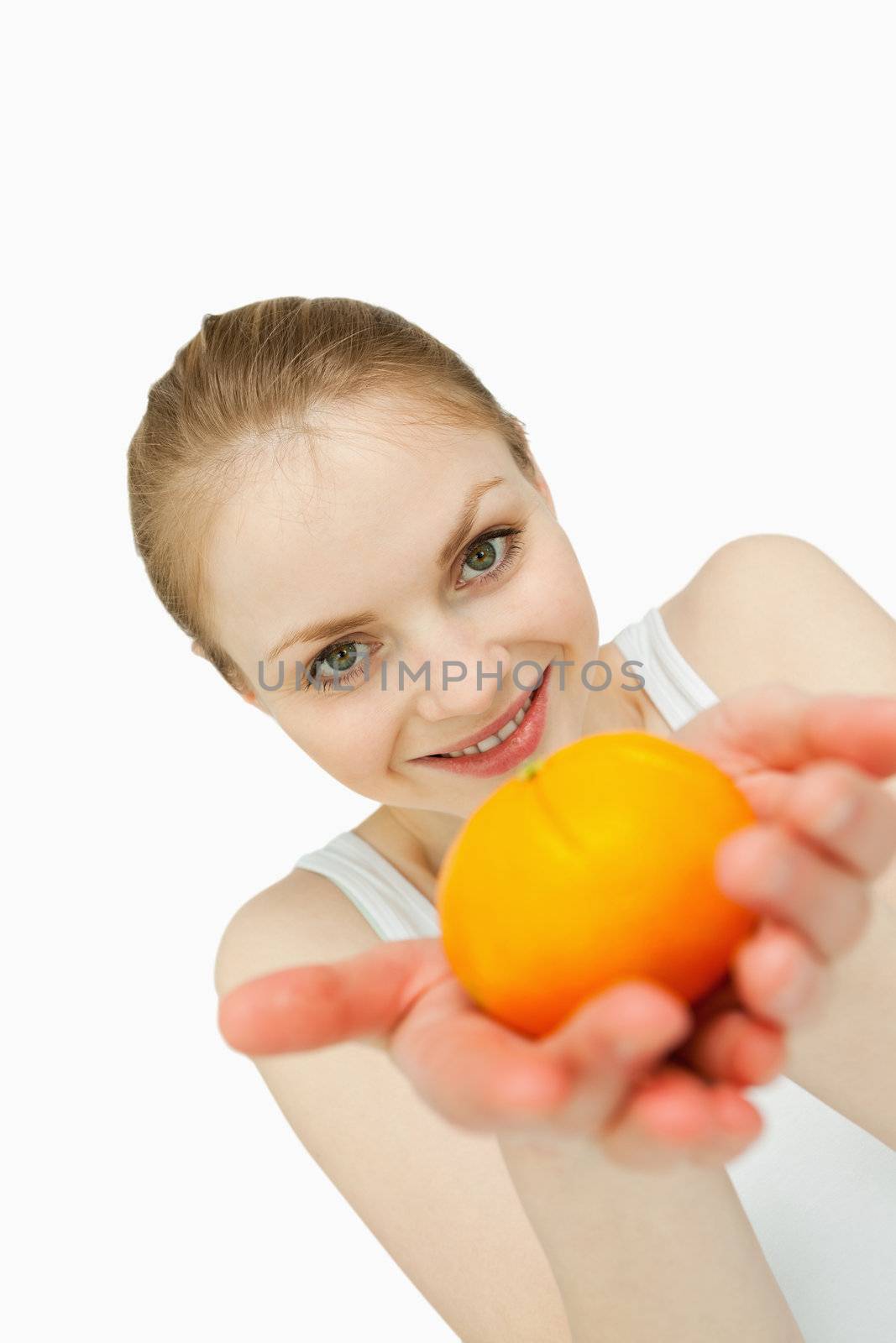 Young woman presenting a tangerine against white background