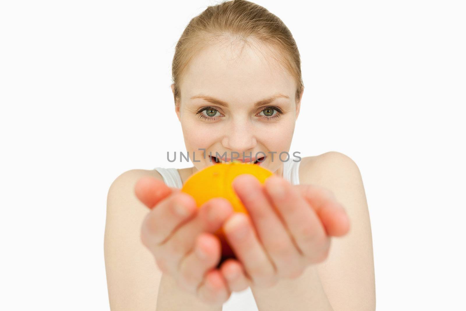 Blonde-haired woman holding a tangerine against white background