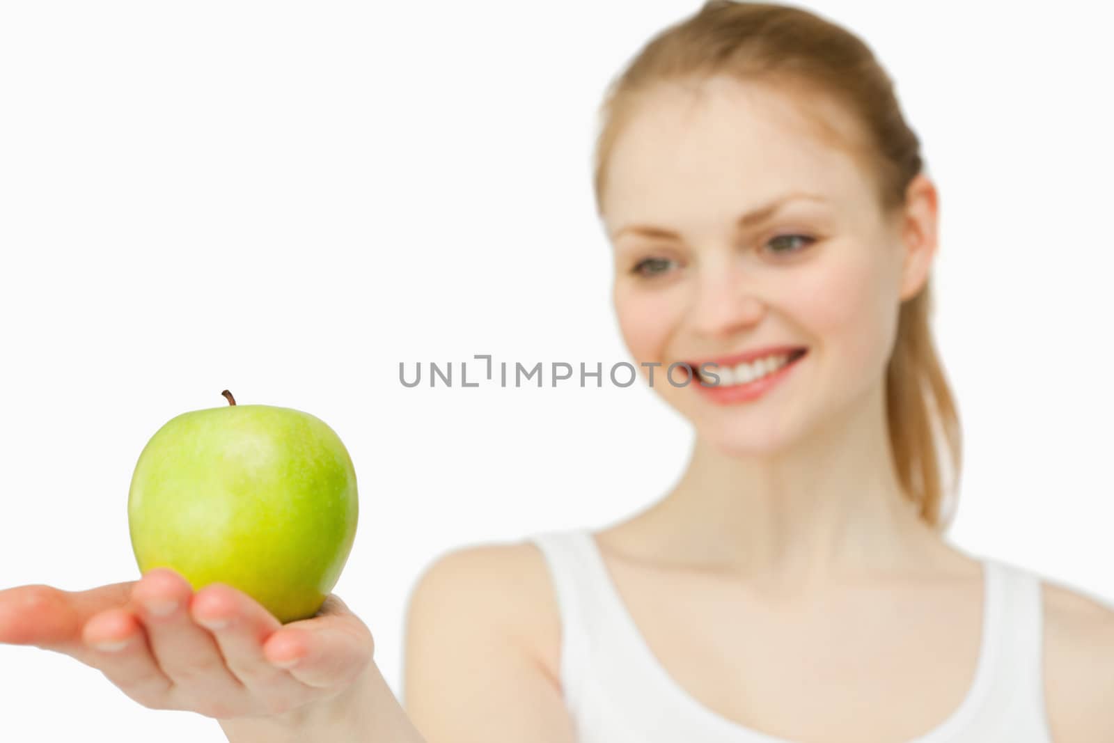 Woman smiling while presenting an apple against white background