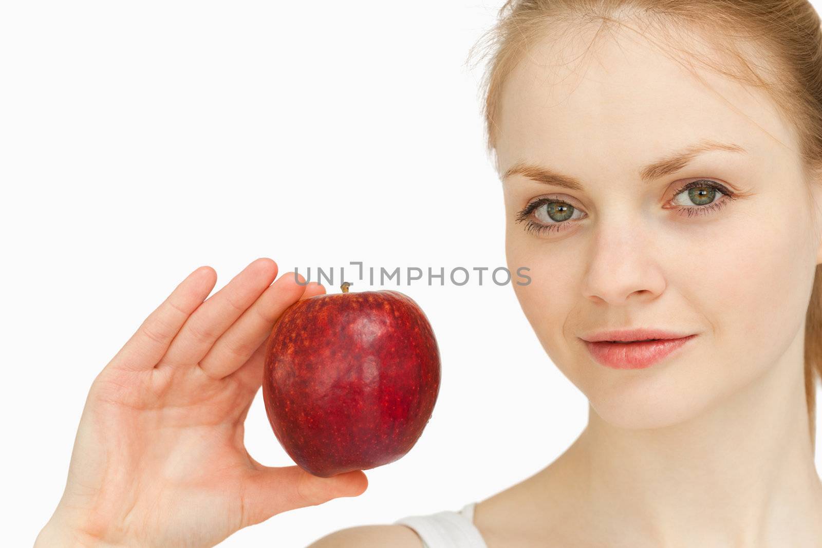 Young blonde-haired woman presenting an apple against white background