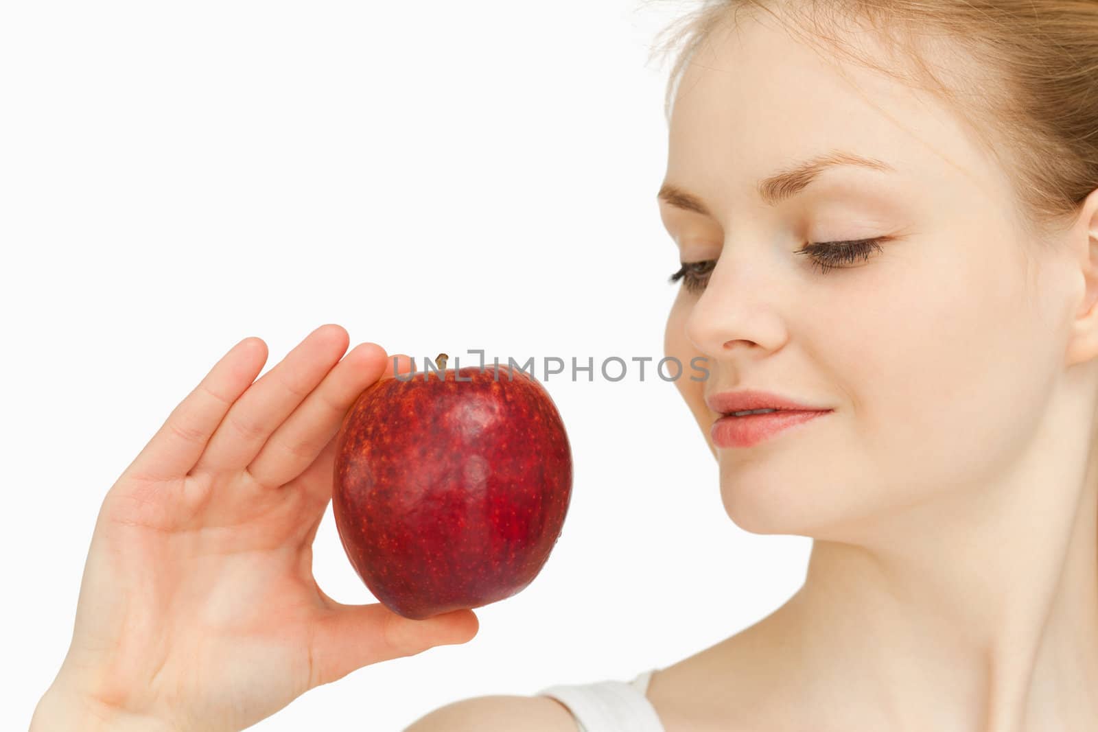 Woman holding an apple while looking at it against white background