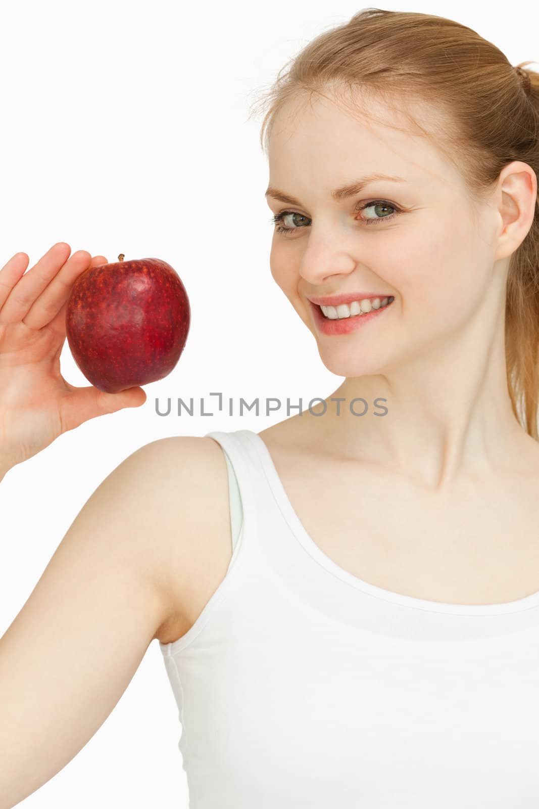 Woman holding an apple while smiling against white background