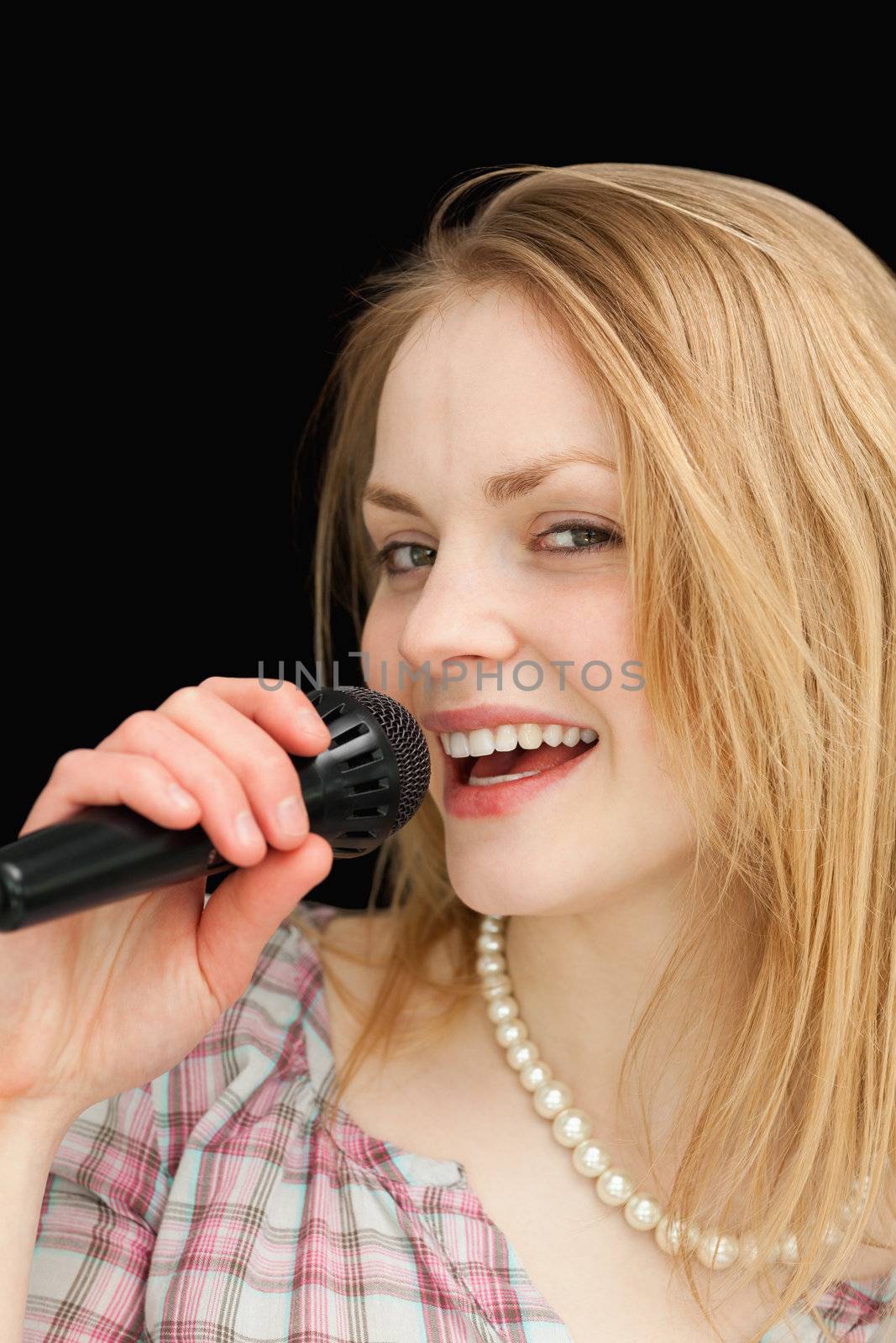 Fair-haired woman singing against black background