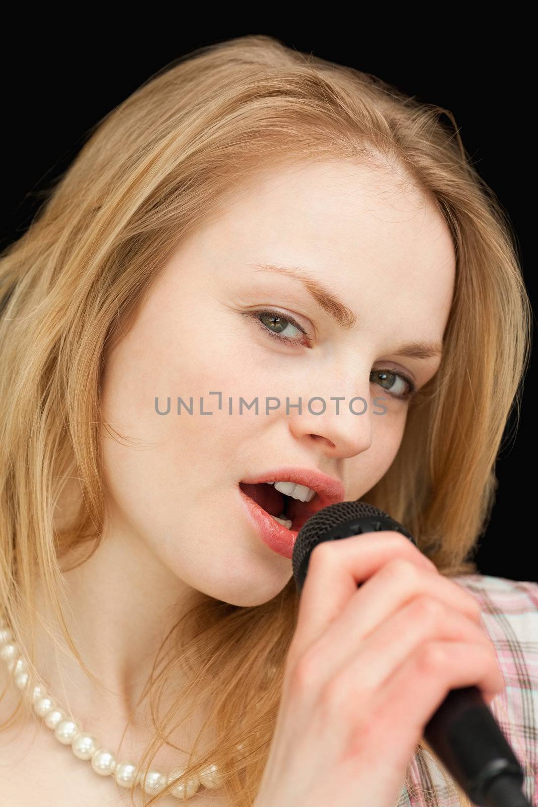 Close up of a woman singing against black background