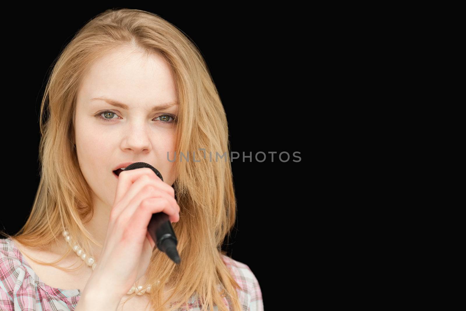 Young blonde-haired woman singing against white background