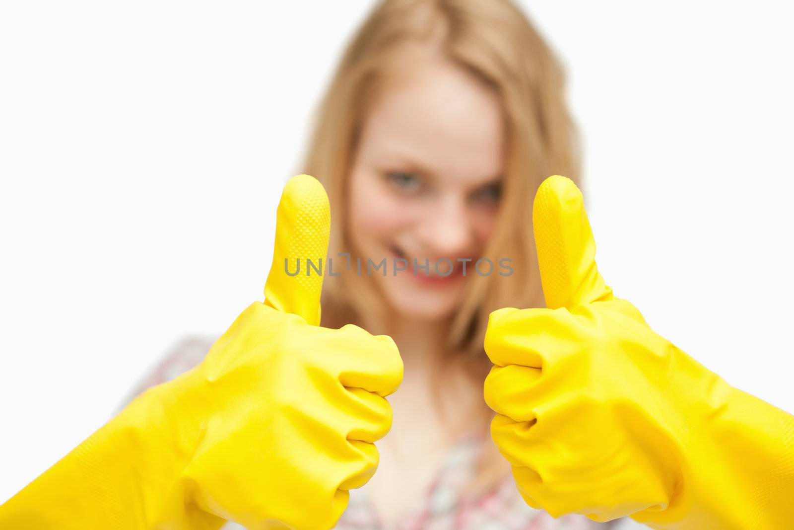 Woman thumbs up while wearing cleaning gloves against white background