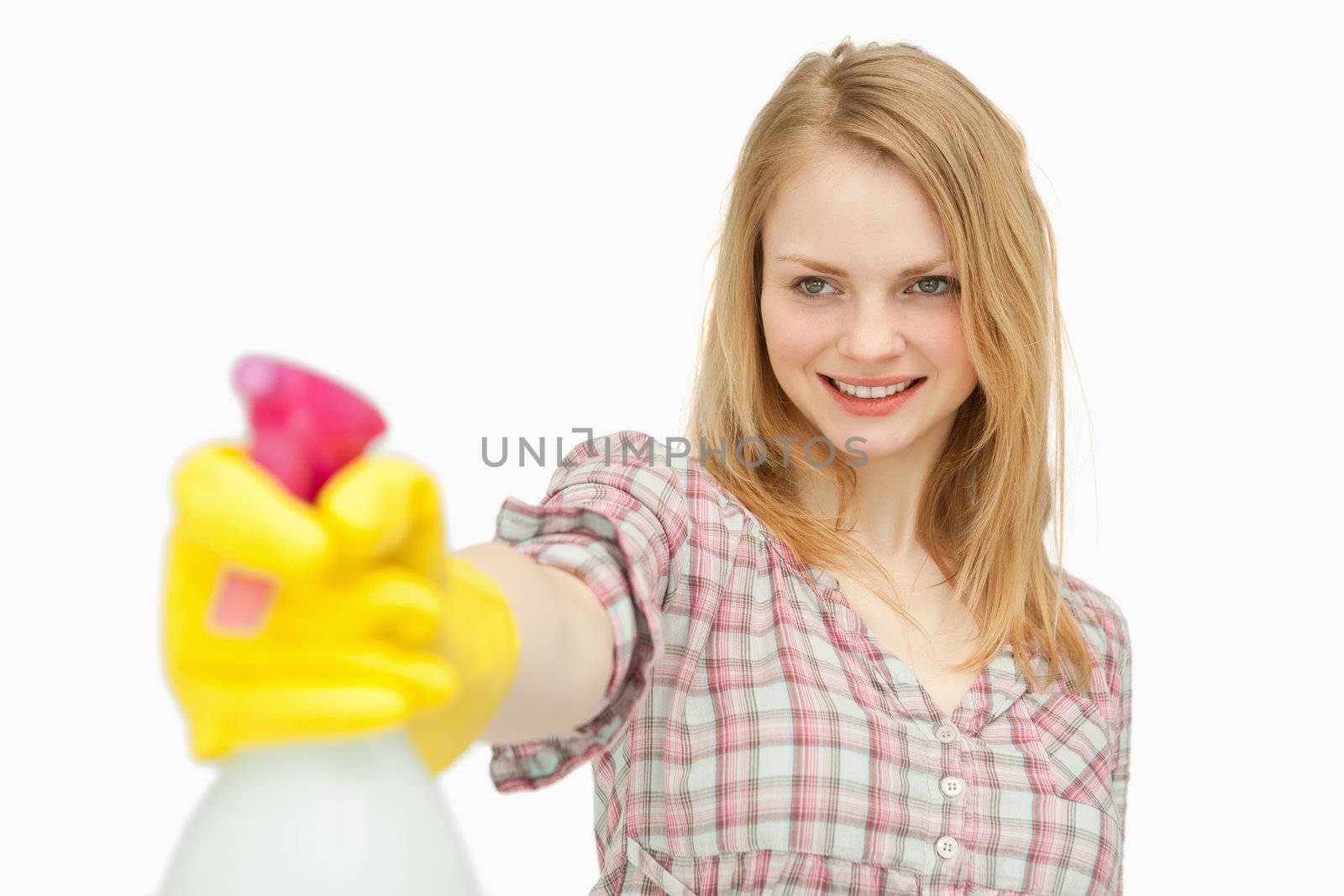 Woman holding a spray bottle while smiling against white background