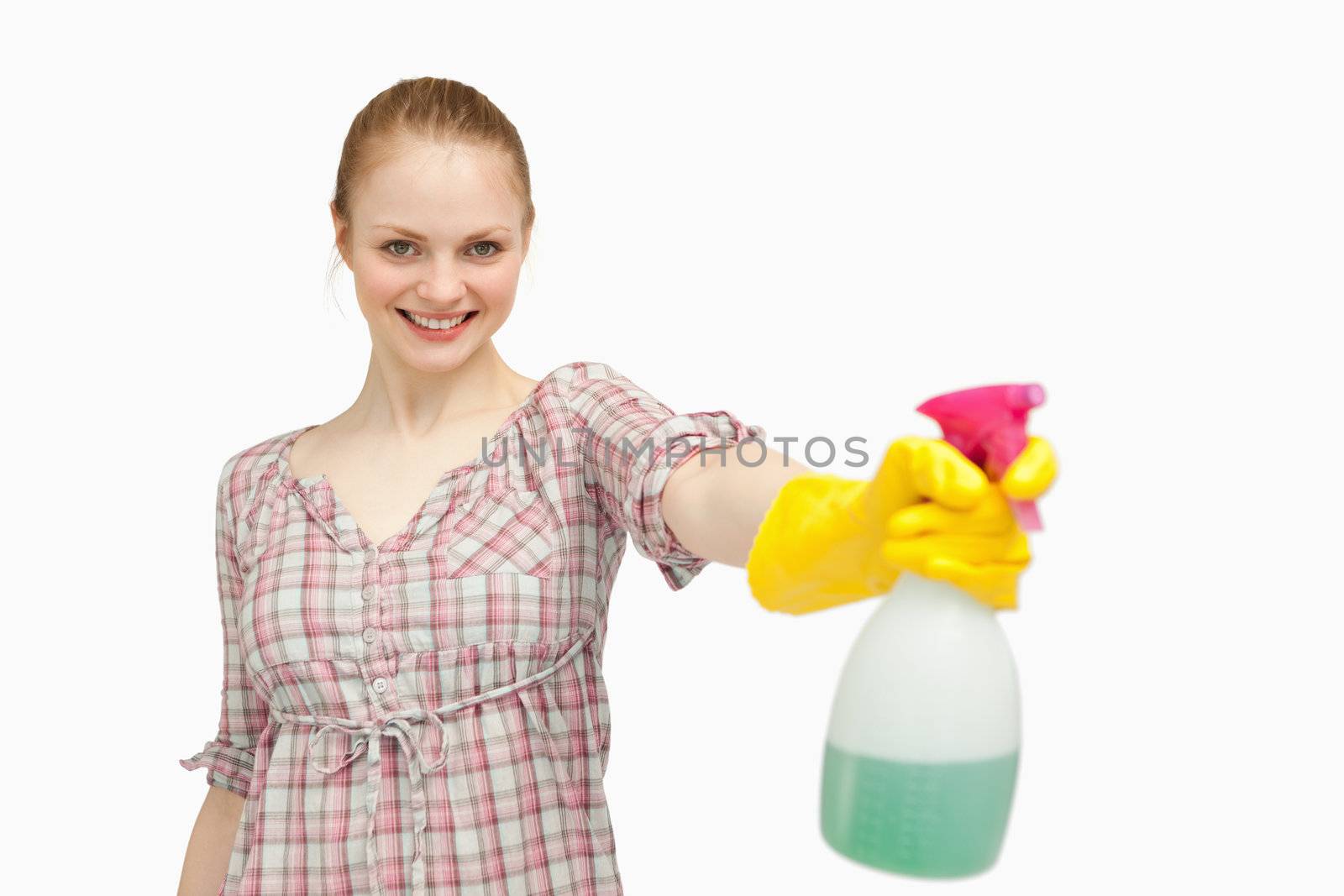 Joyful woman holding a spray bottle while smiling against white background