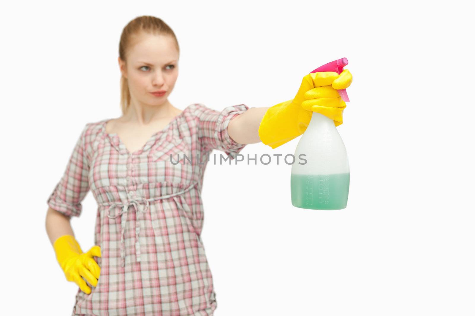 Serious woman holding a spray bottle while looking away against white background