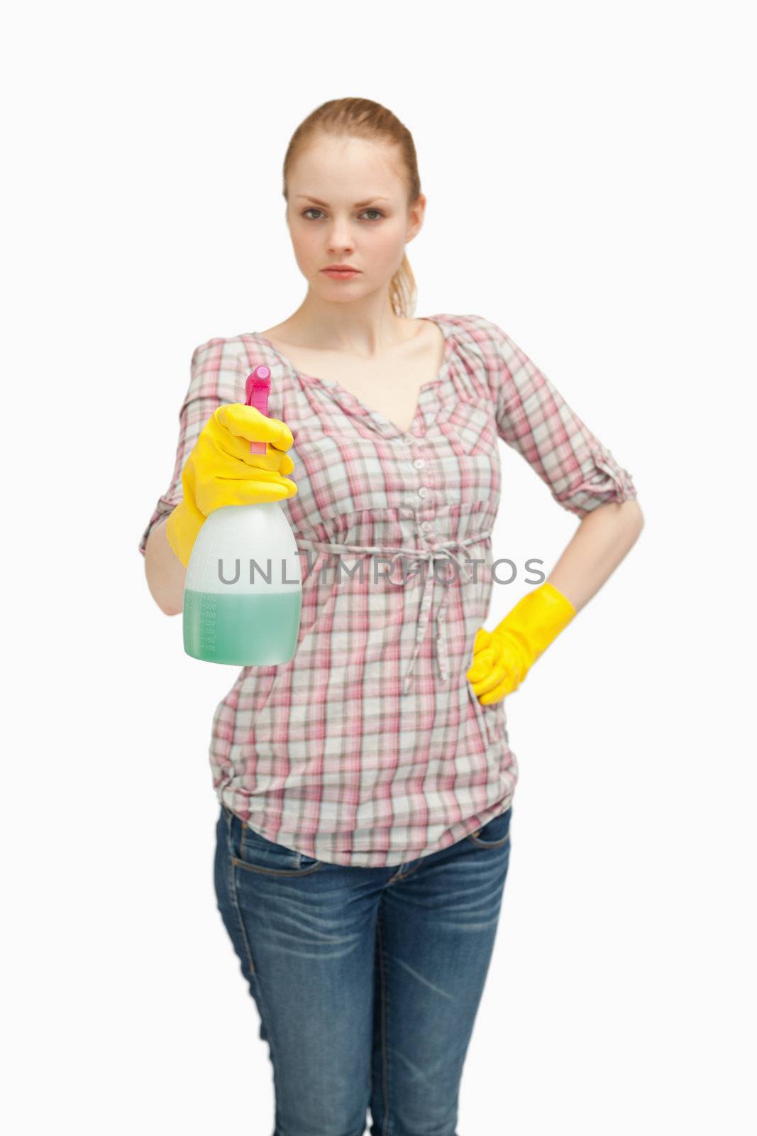 Serious woman holding a spray bottle while standing against white background