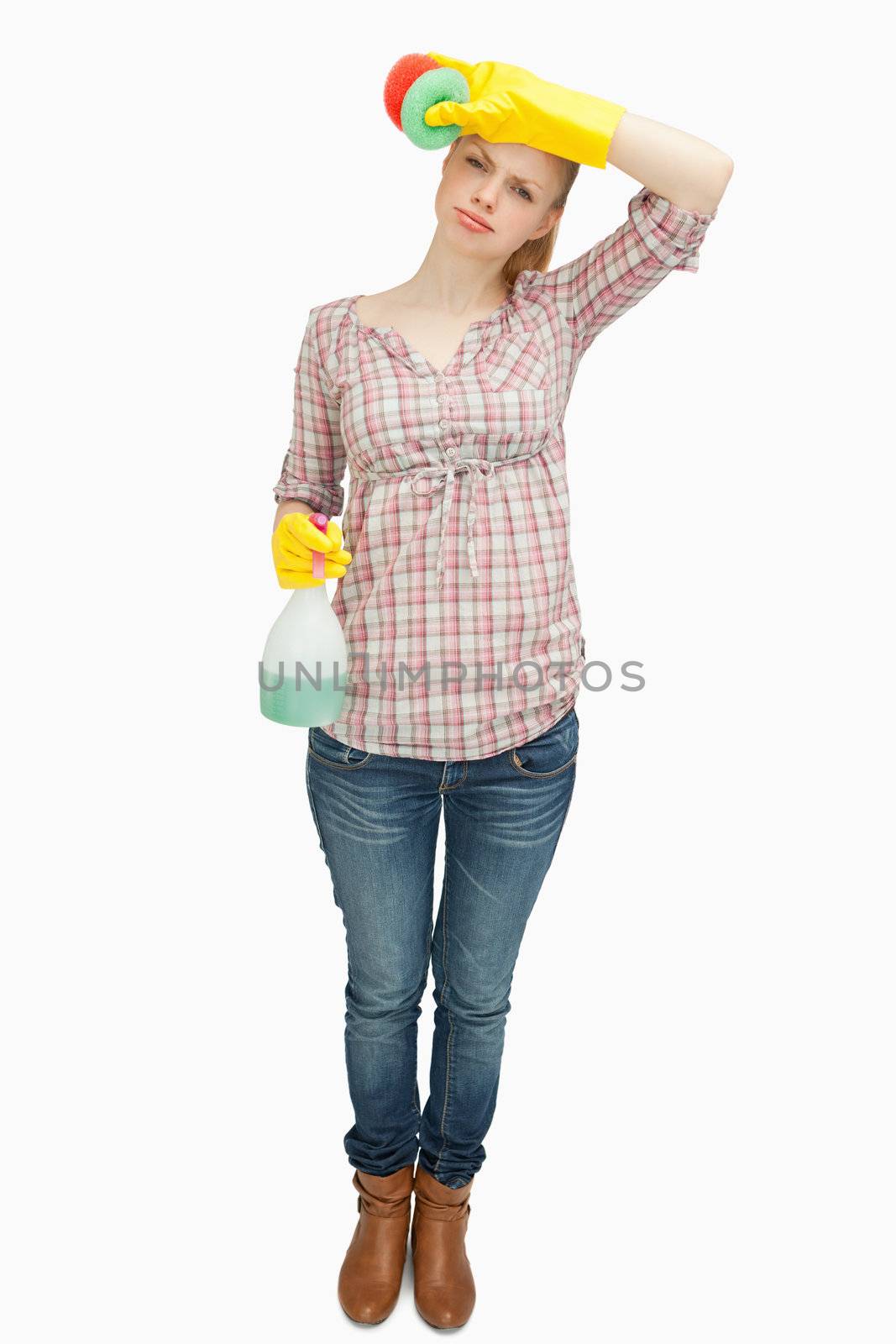 Woman wiping her forehead while holding a spray bottle  against white background