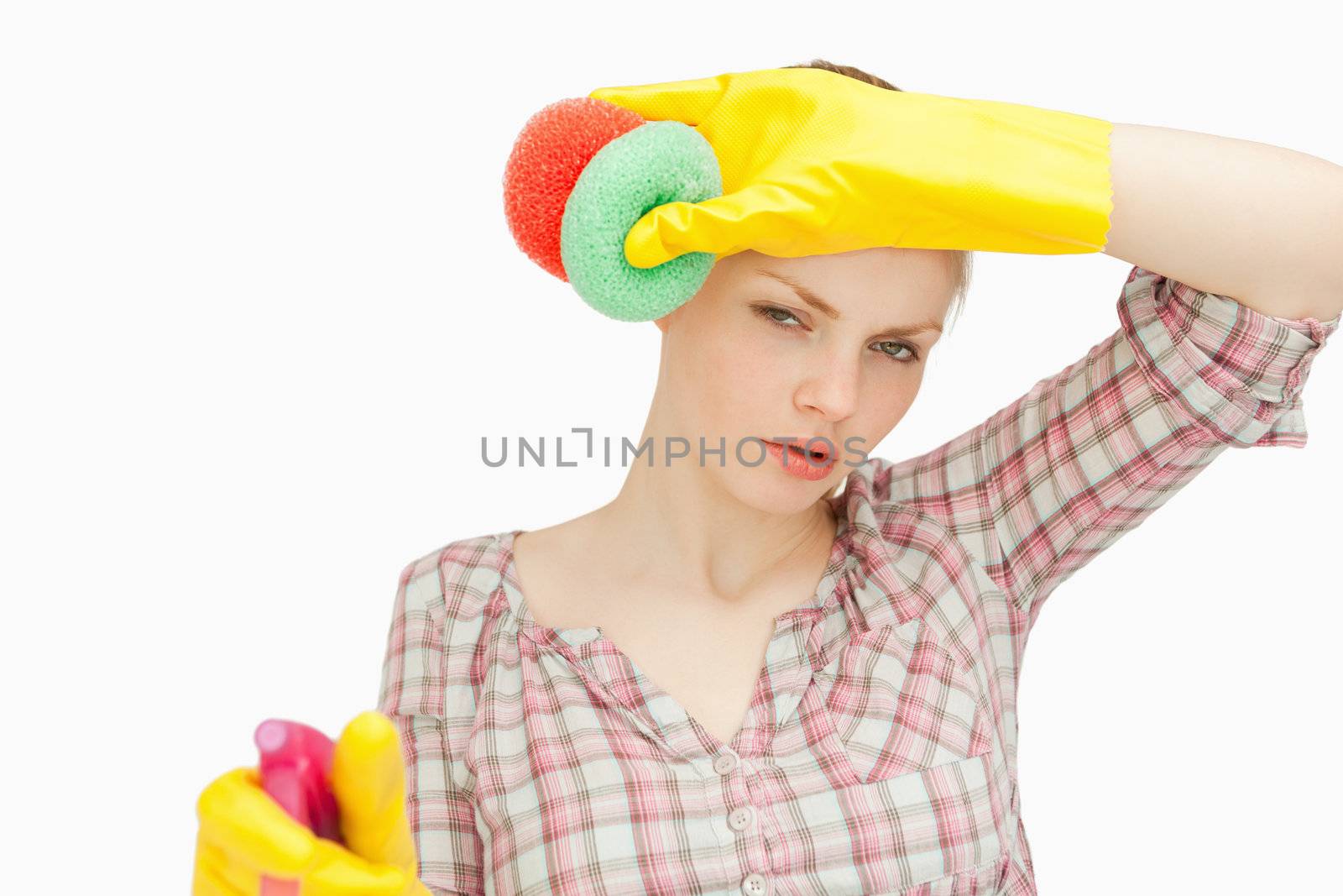 Woman wiping her frown while wearing cleaning gloves against white background