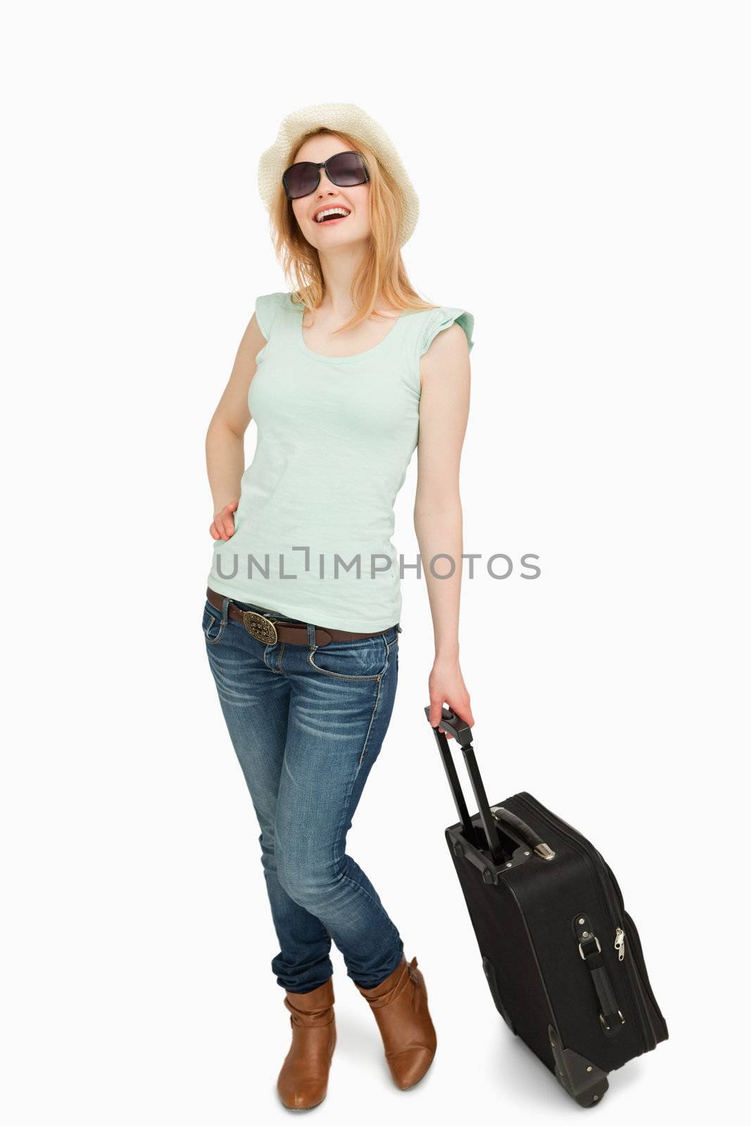 Young woman smiling while holding a suitcase against whitebackground