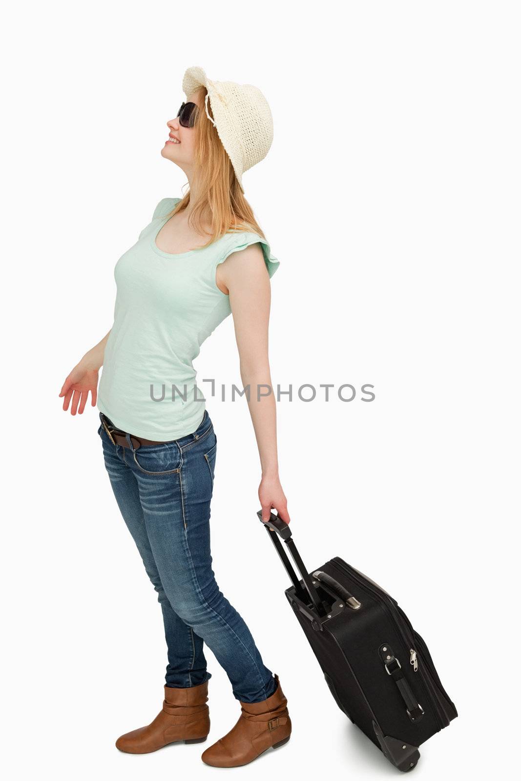 Young woman smiling while holding a suitcase against white background