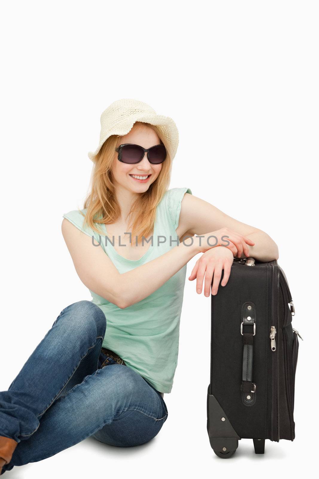 Woman sitting near a suitcase against white background