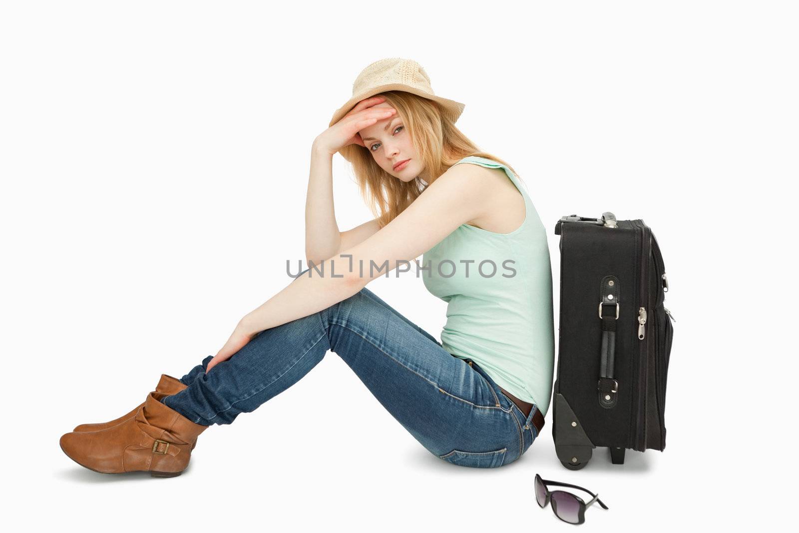 bored woman sitting near a suitcase against white background