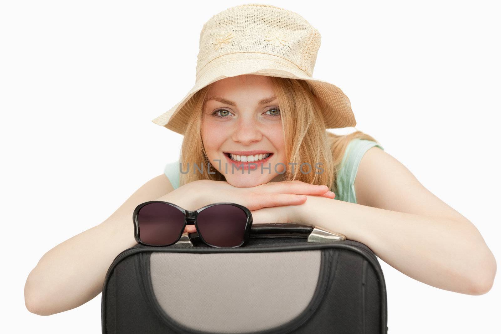 woman leaning on a suitcase while smiling against white background