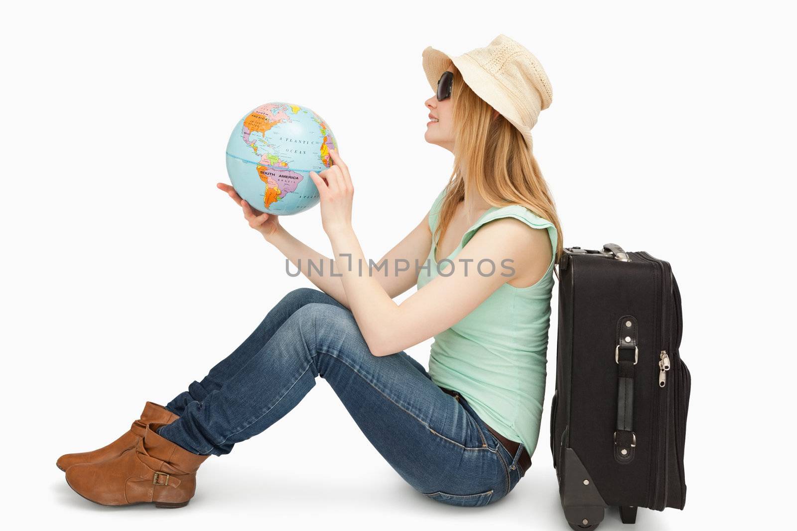 Woman sitting while holding a world globe against white background