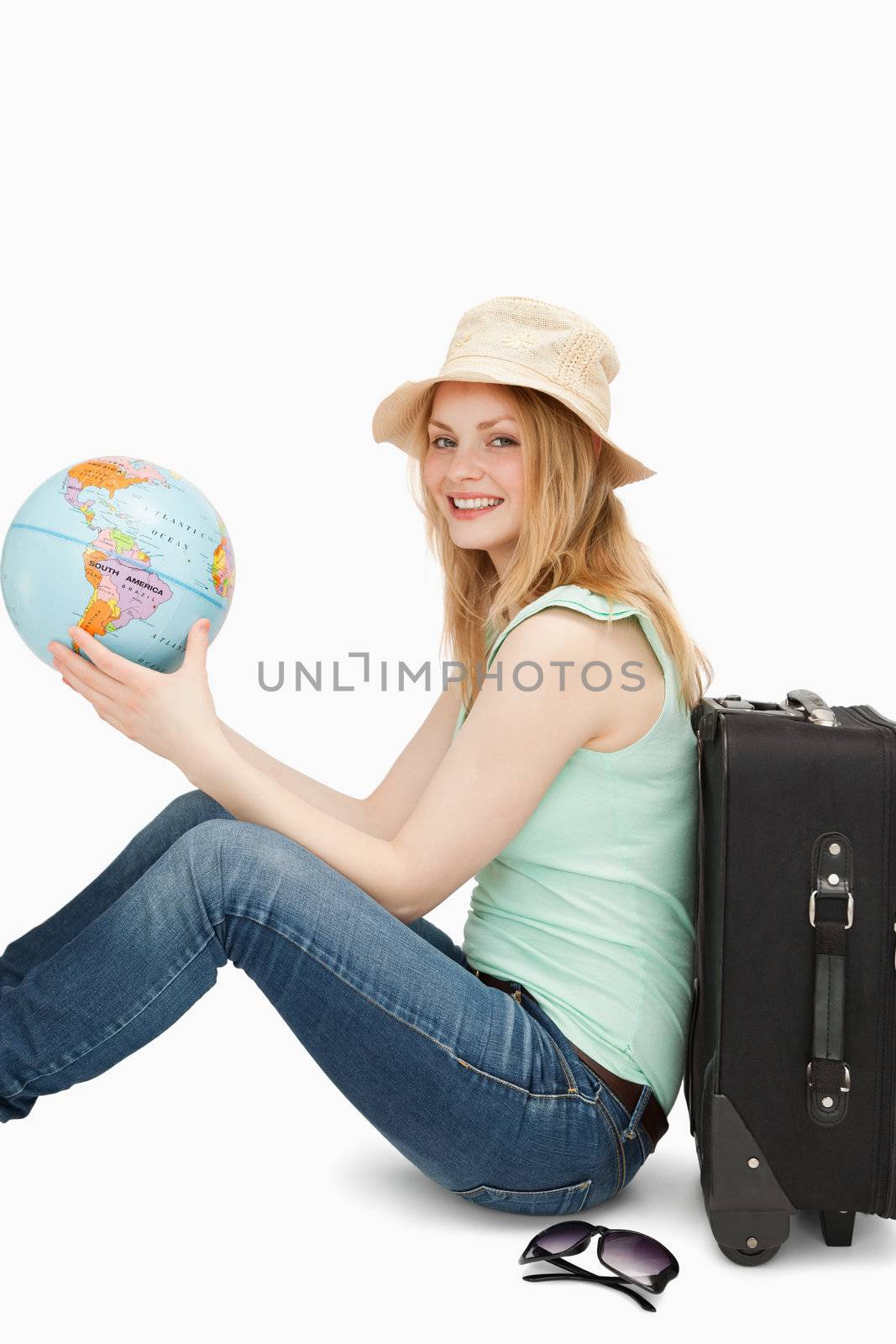 Young woman smiling while holding a world globe against white background