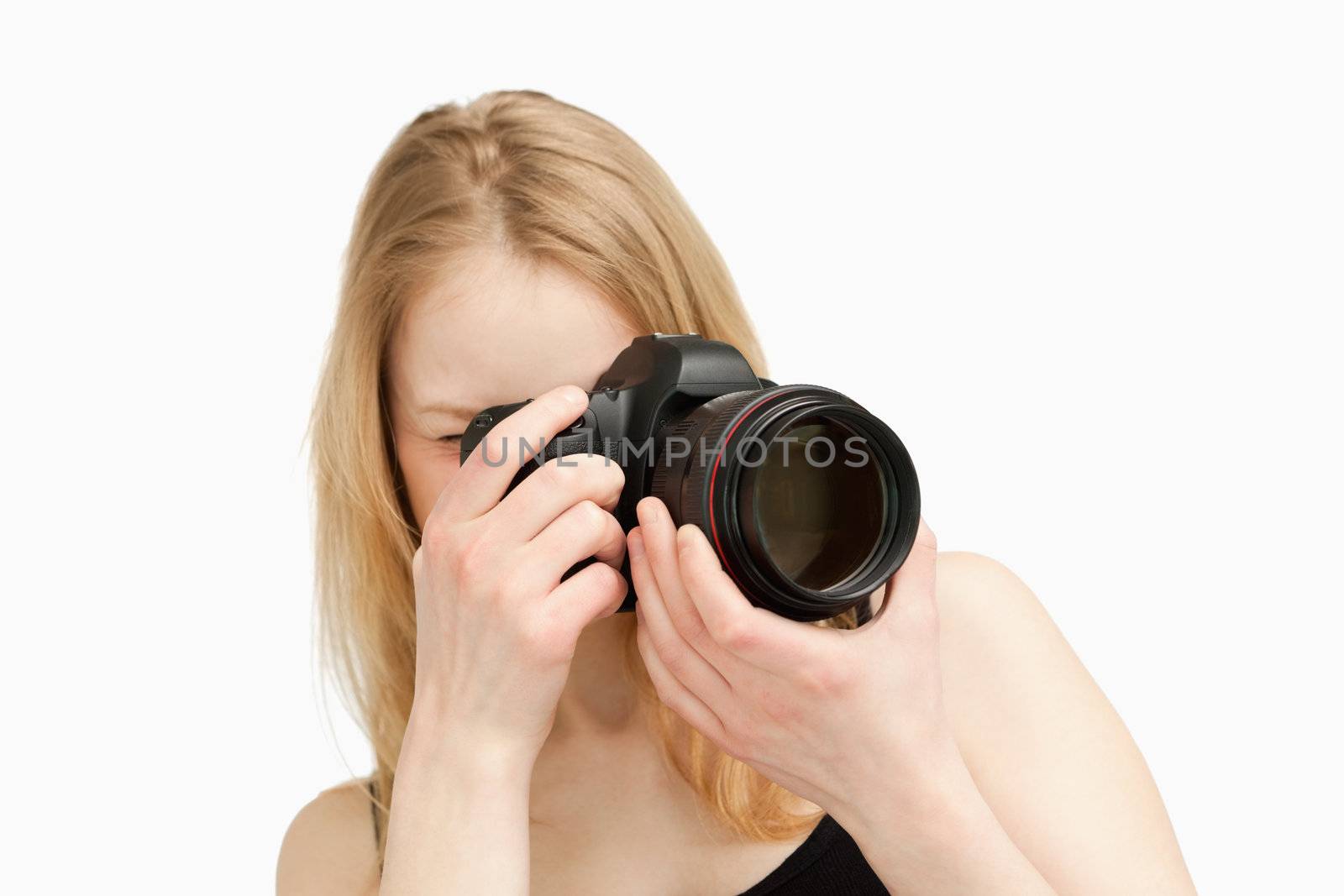 Woman taking a photography with a single-lens reflex camera against white background
