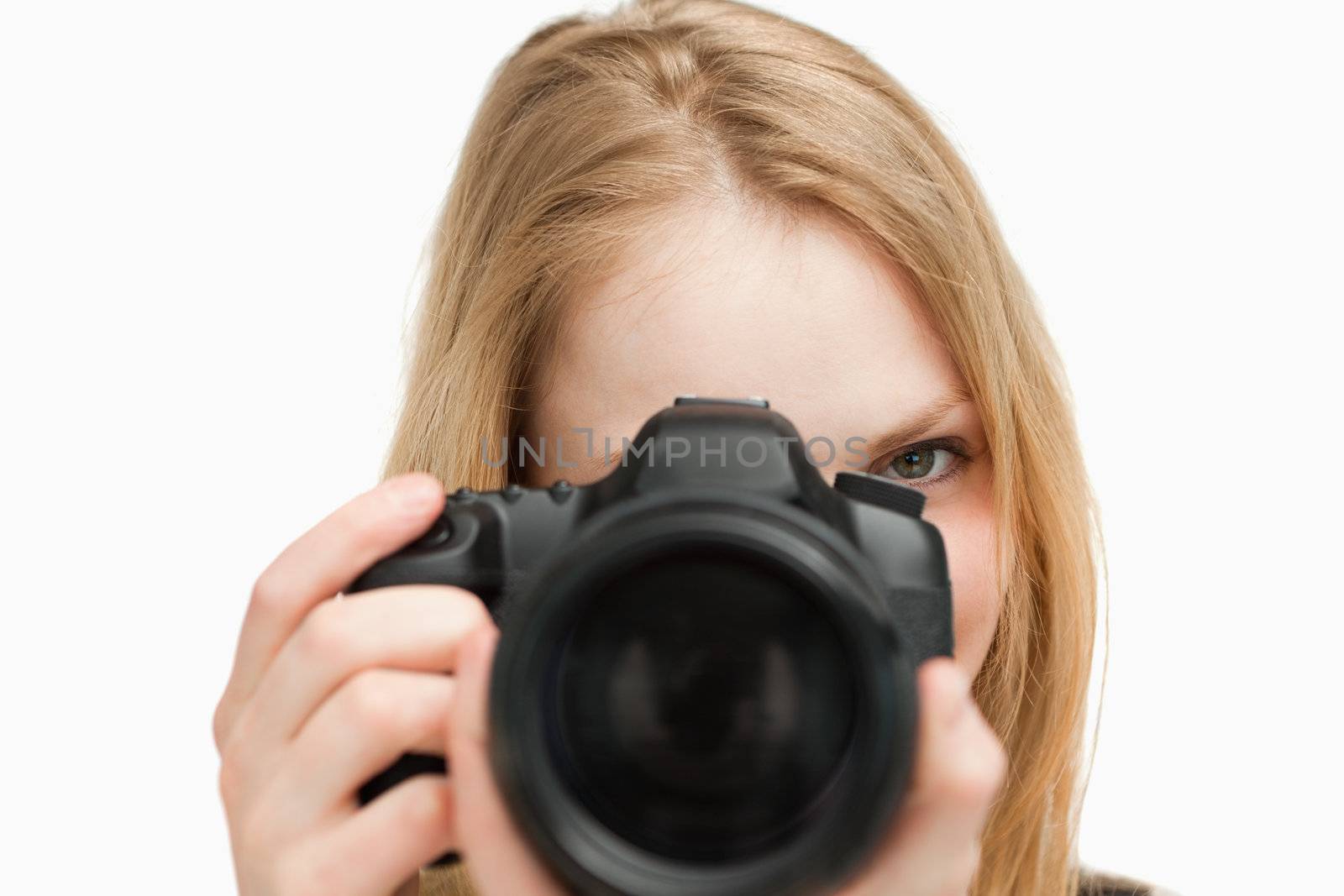 Young woman holding a camera against white background