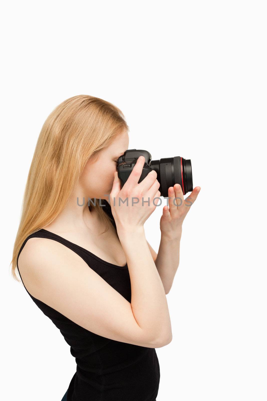 Blonde-haired woman aiming with a camera against white background