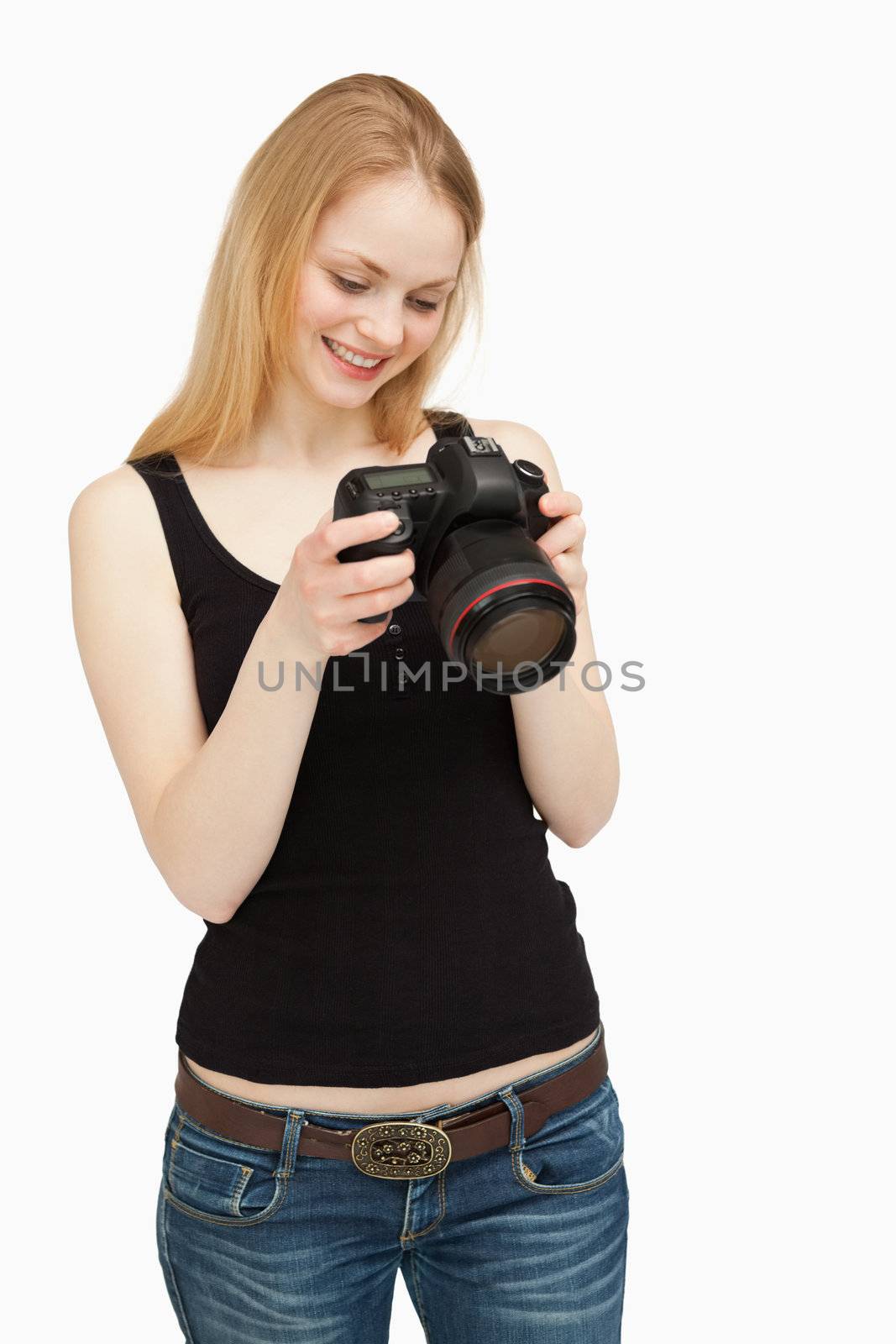 Woman looking at the screen of her camera while smiling against white background