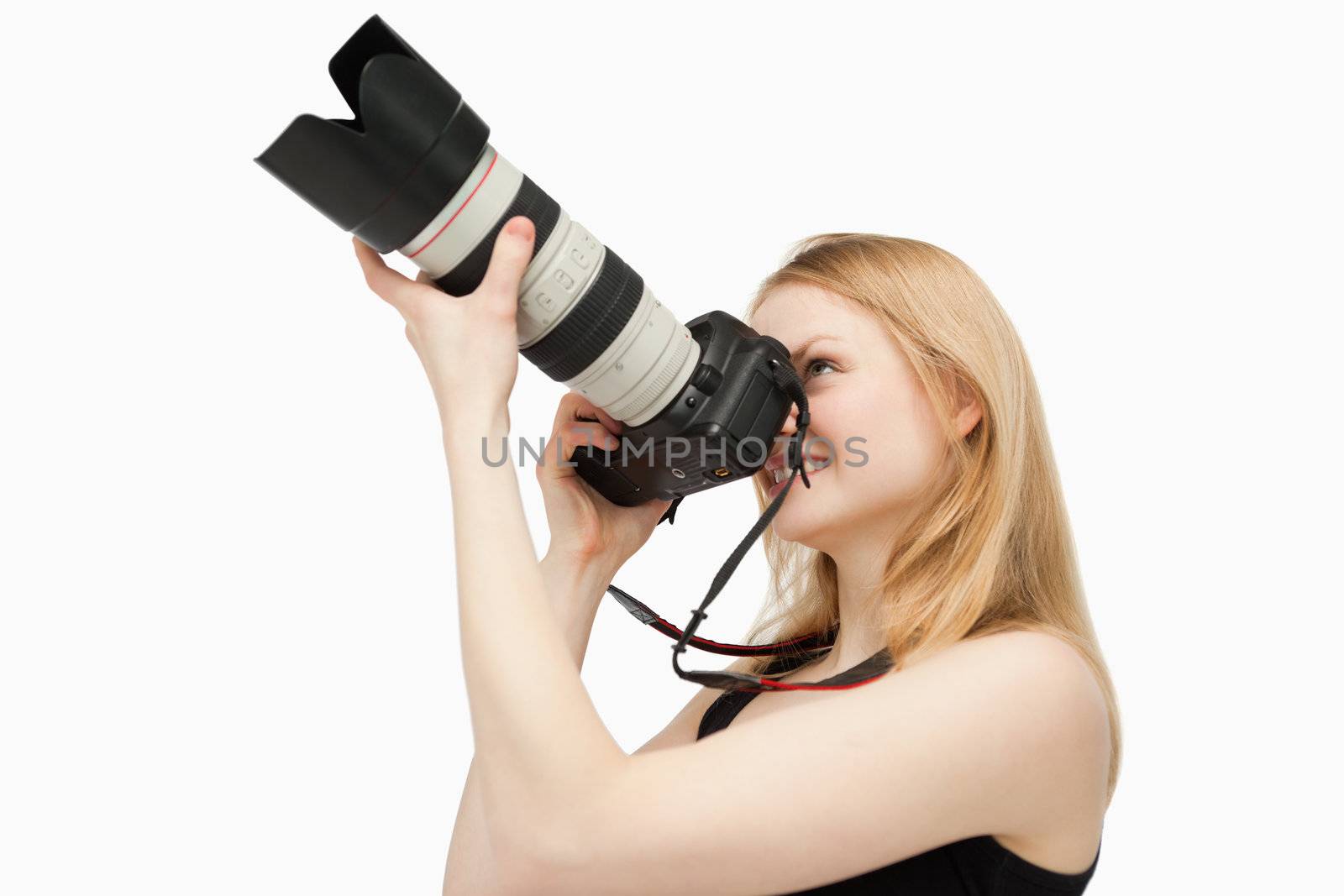 Woman aiming with a SLR camera while smiling against white background