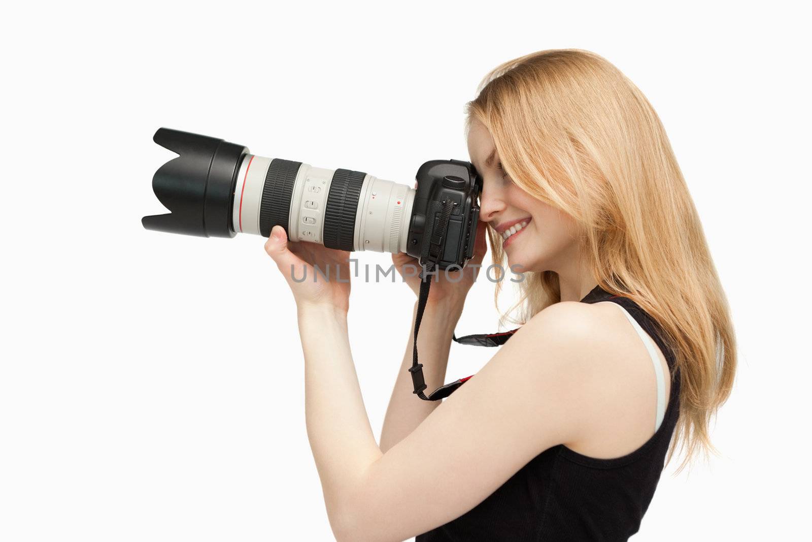 Woman smiling while holding a SLR camera against white background