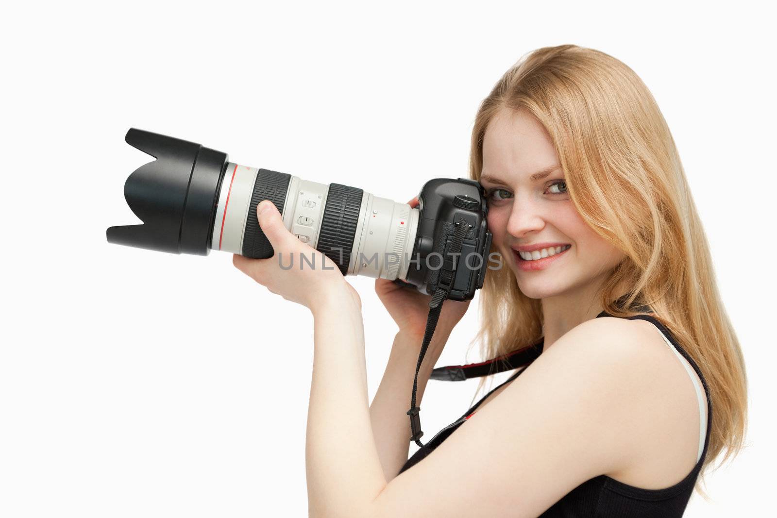 Woman looking at the camera while holding a camera against white background