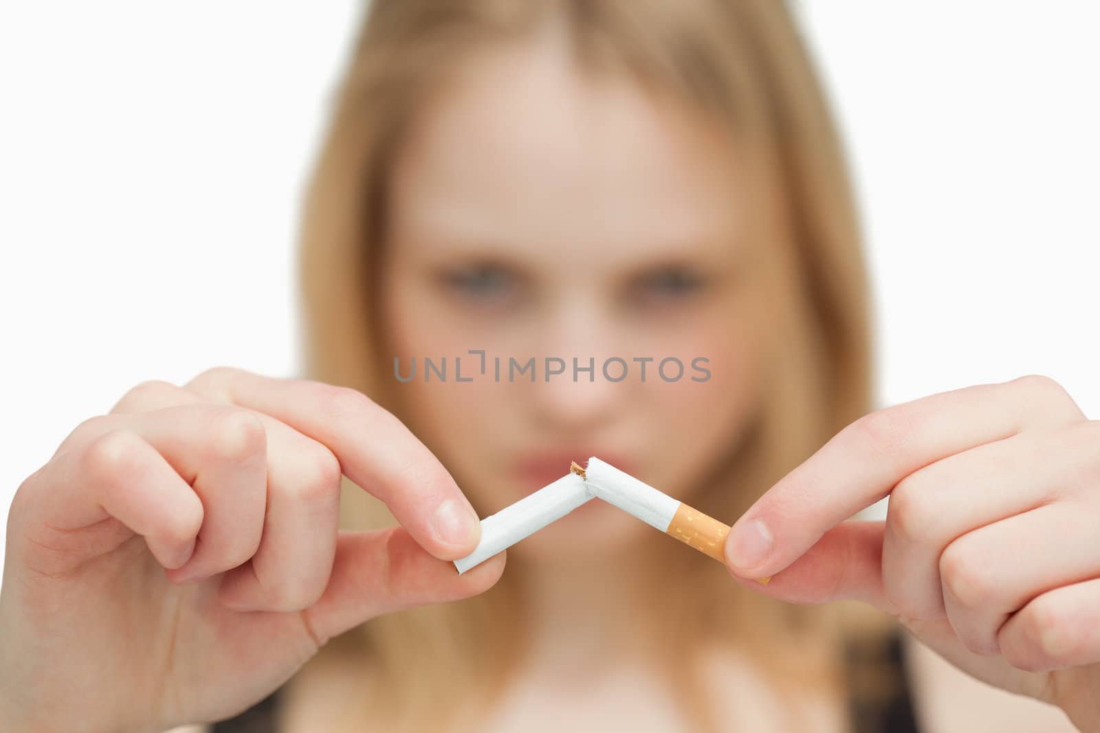 Close up of a woman breaking a cigarette against white background