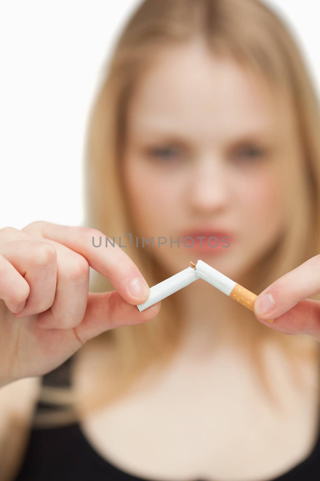 Close up of a blonde-haired woman breaking a cigarette against white background