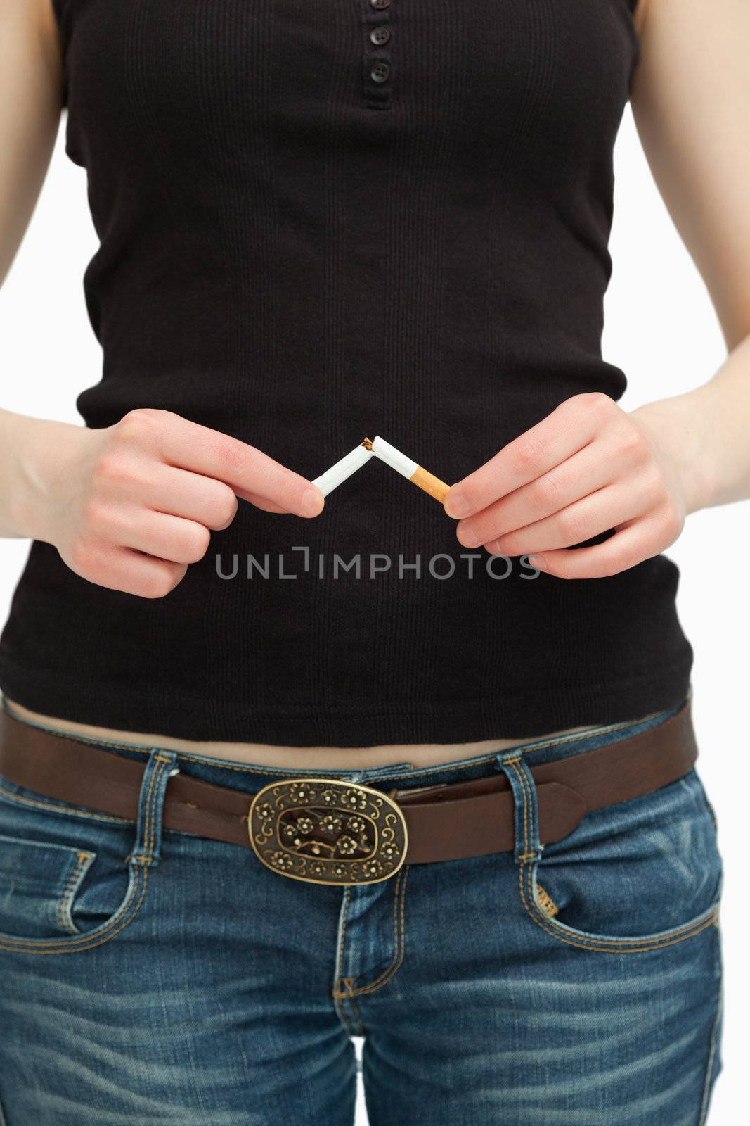 Woman breaking a cigarette with her hands against white background