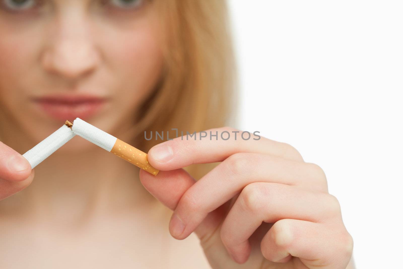 Close up of the hands of a woman breaking a cigarette against white background