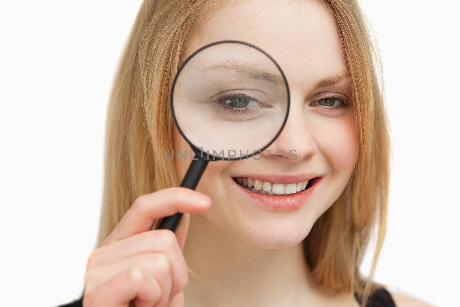 Woman placing a magnifying glass on her eye against white background