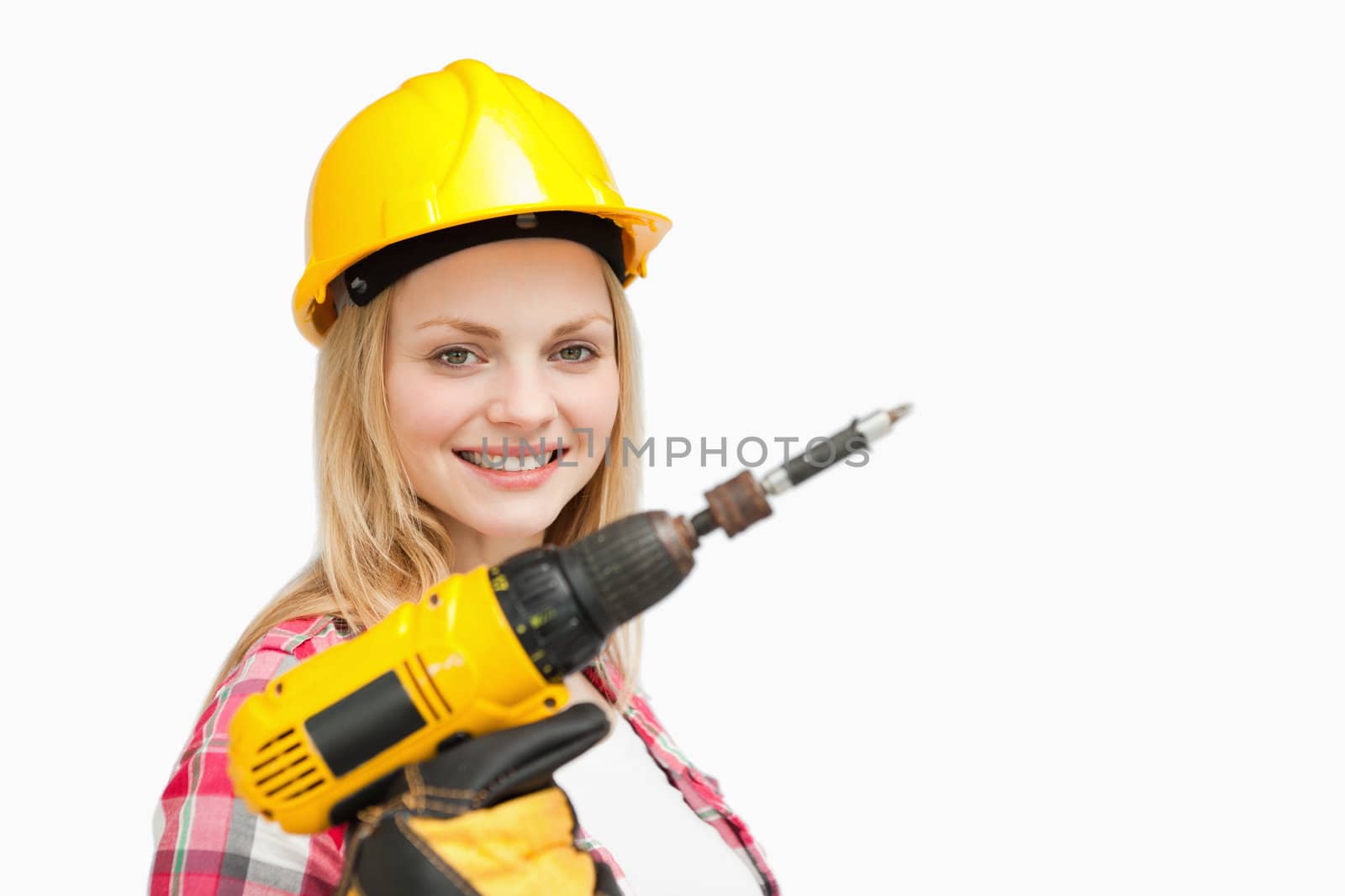 Woman holding an electric screwdriver while smiling against white background