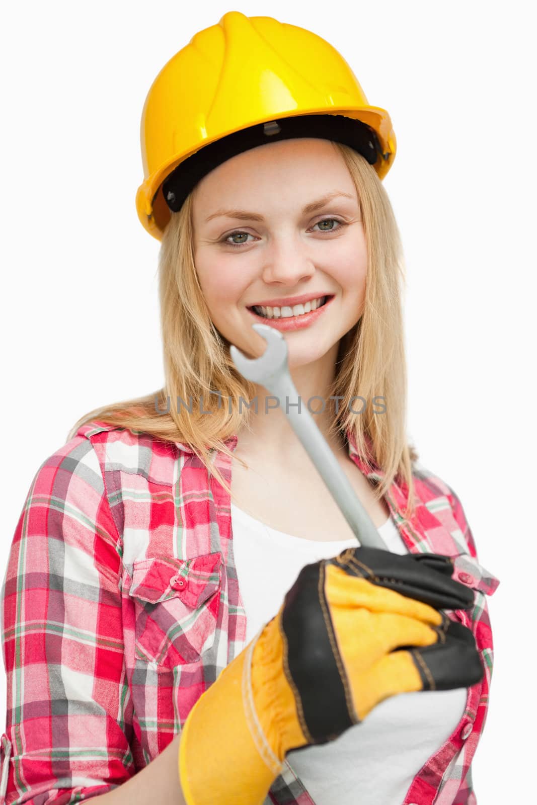 Woman holding a wrench while standing against white background
