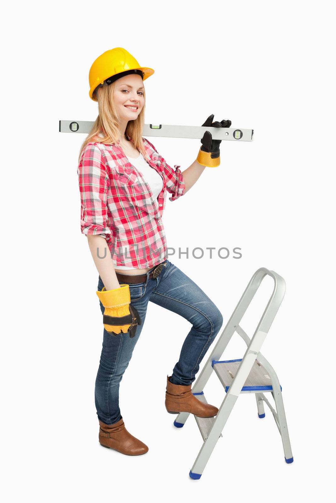 Woman holding a spirit level next to a step ladder against white background
