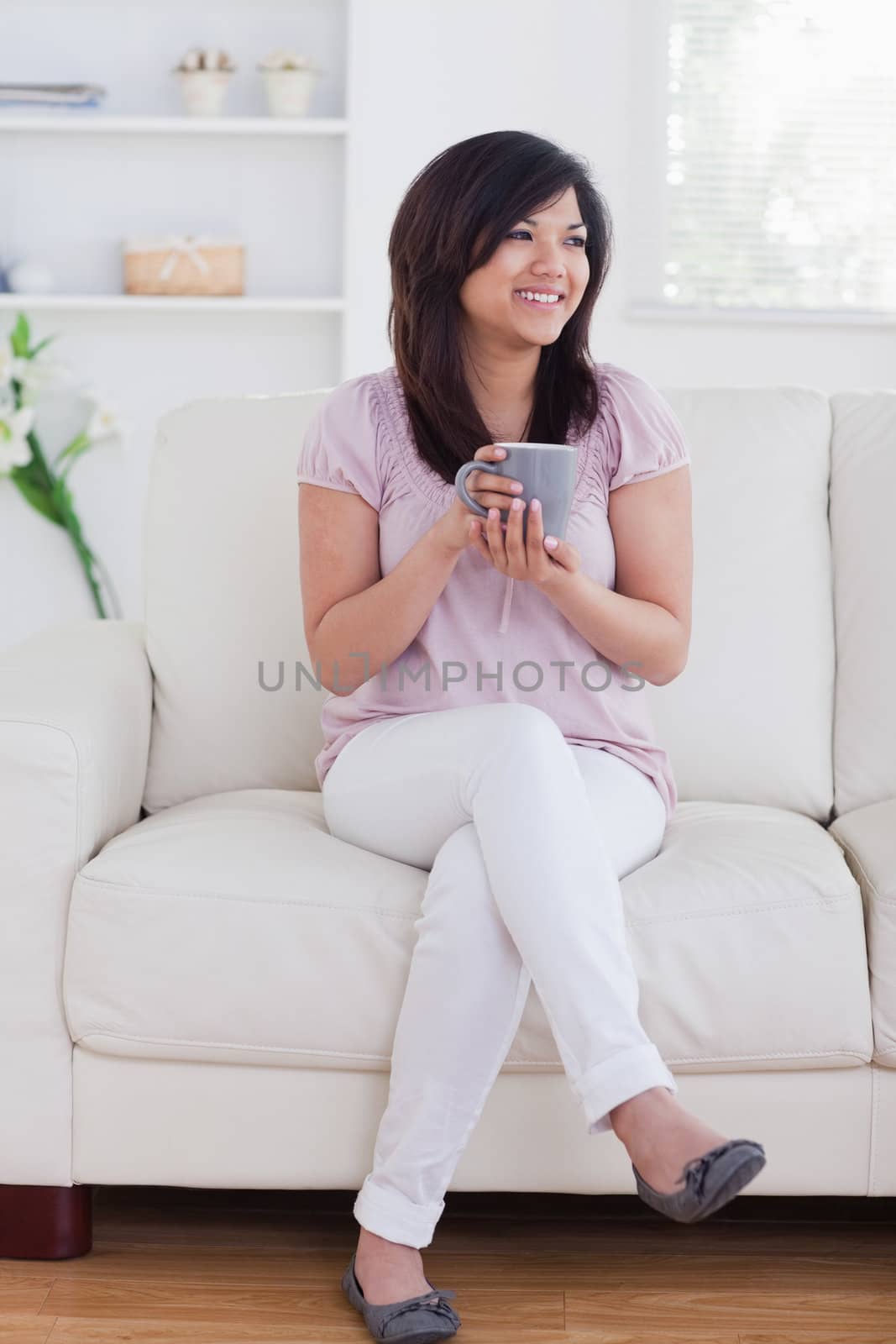 Woman sitting on a sofa while she is smiling in a living room