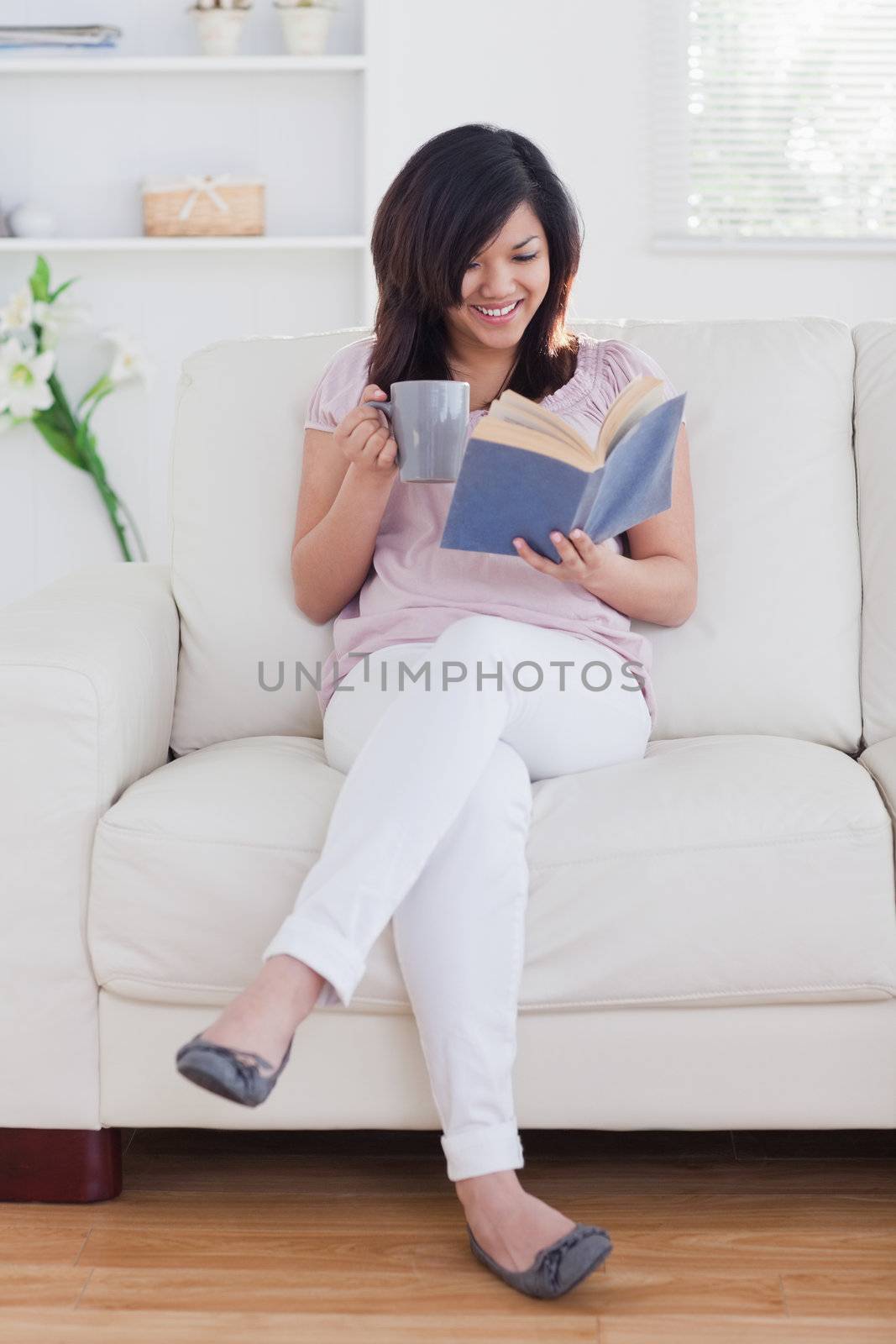 Woman reading a book while sitting on a couch in a living room