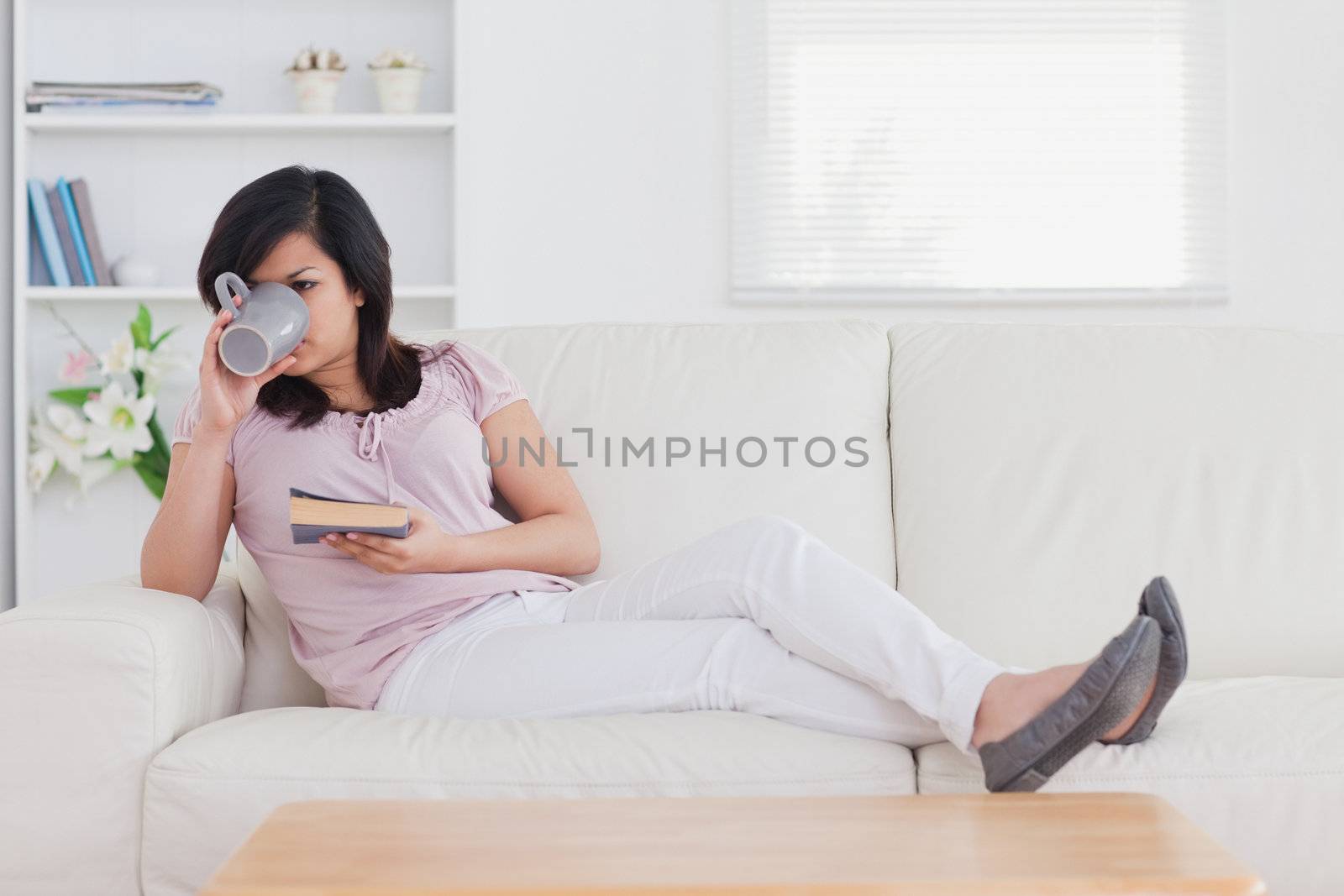 Drinking woman lying on a couch in a living room