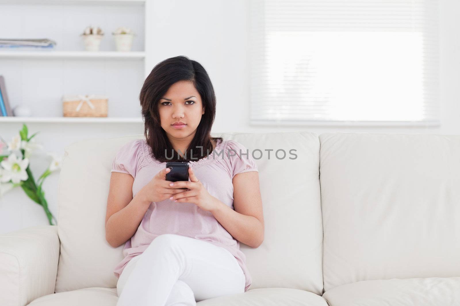 Woman sitting on a couch while holding a phone in a living room