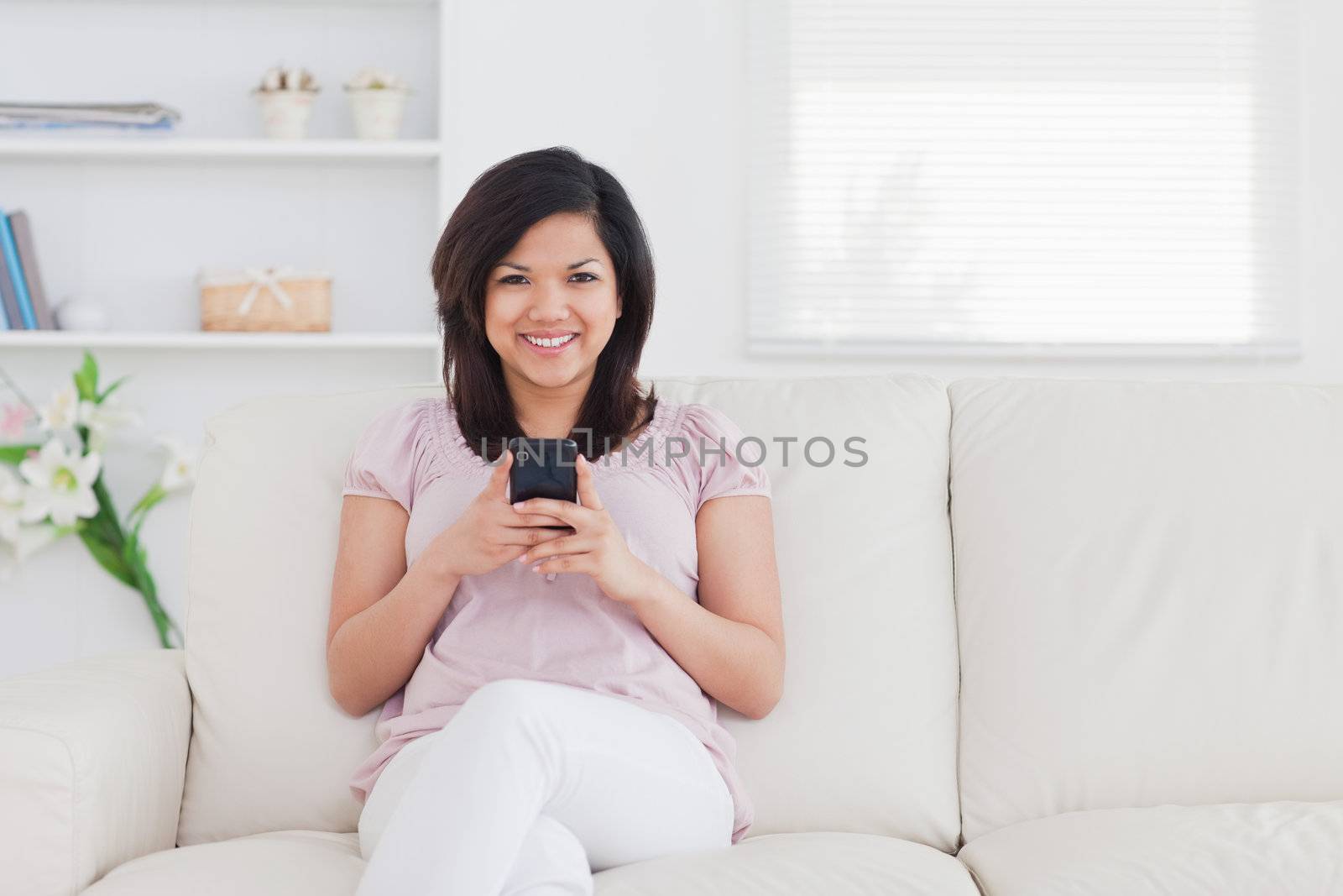 Woman sitting on a sofa while holding a phone