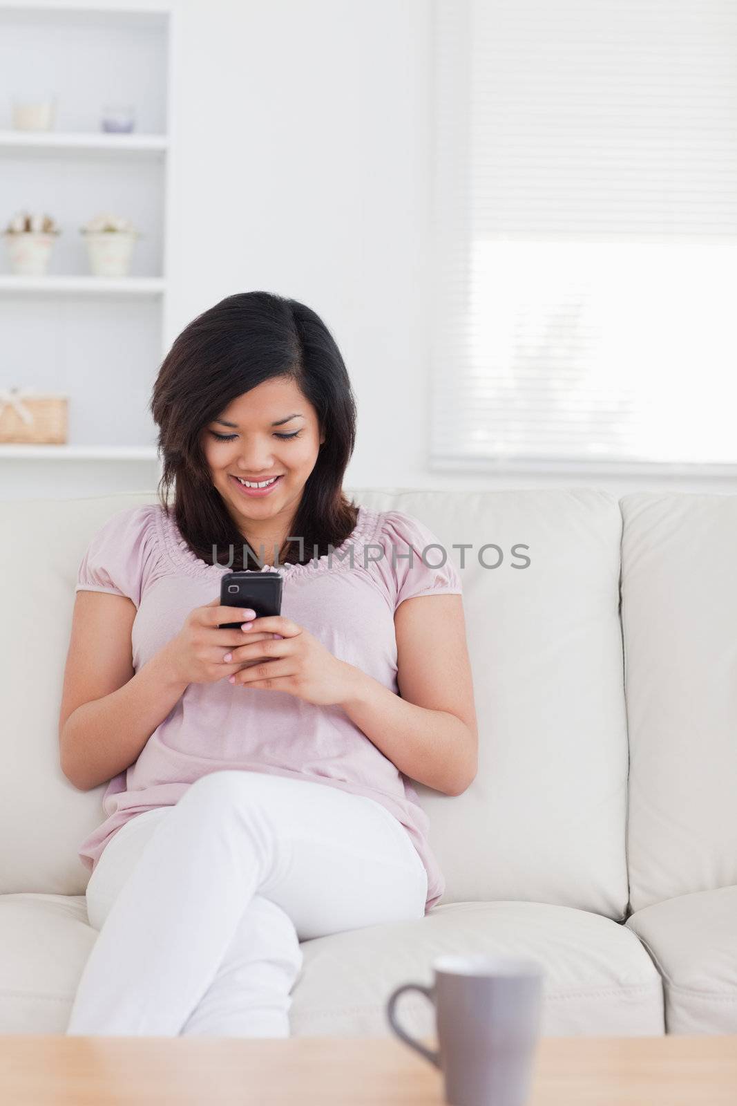 Woman sitting on a couch and holding a phone in a living room