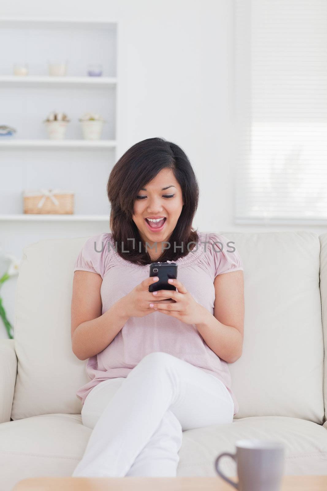 Woman surprised while looking at a phone in a living room
